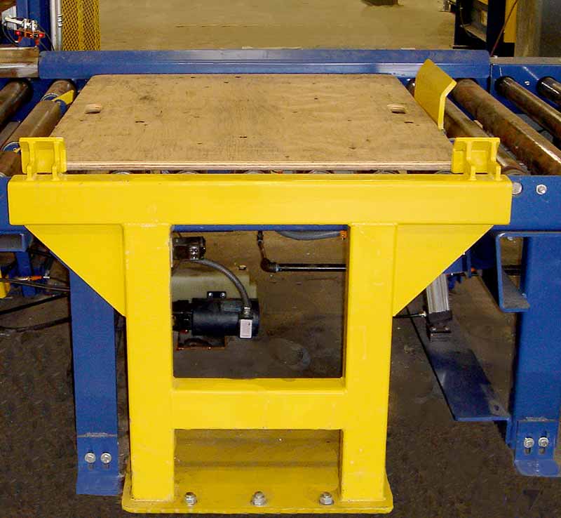 Air operated stop used in conjunction with anti-back up dogs for precision slave pallet positioning (slave shown with no load present – designed for 2,500 pound loads in dry-goods distribution center).